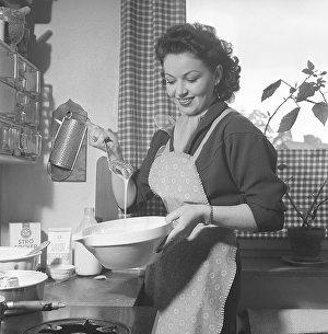 Woman baking in the past. A young woman whips together sugar and other ingredients into a batter