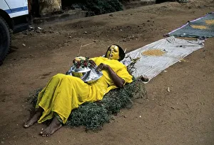 A woman begging lying on a bed of thorns in front of temple