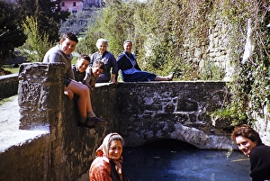 Woman and boys of an Italian family sitting on a bridge in a village, Italy 1957