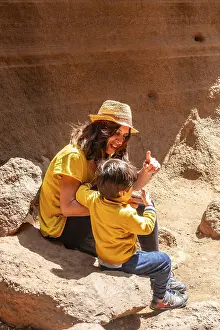 A woman and a child are sitting on a rock in a desert