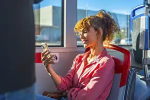 Woman on a city bus smiling while scrolling smartphone