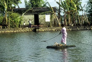 A woman crossing the Backwaters with the help of the rope and a country made float