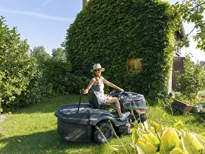 Woman driving lawn mower, lawn tractor