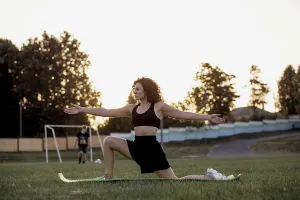 Woman extending arms while performing a yoga pose in a park during sunset