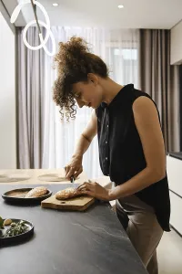 A woman is focused on cutting duck fat in a kitchen