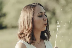Woman in a garden blows away a dandelion