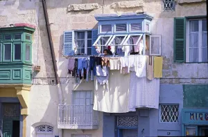 Woman hanging laundry out the window to dry in an old residential neighbourhood of Valletta, Malta 1978