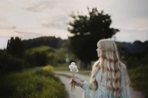 A woman holding a bouquet of dandelions on a countryside path