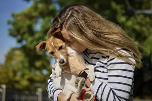 Woman holds her dog on hands and embracing with it
