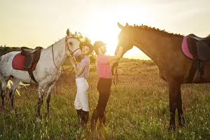 Two woman and two horses outdoor in summer happy sunset together nature