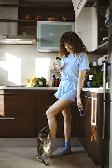 A woman is in the kitchen wearing a light blue outfit