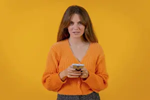 A woman looking at things on the internet on the mobile phone on a yellow background