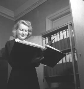 Woman in an office in 1942. A young female employee flips through the content of a binder