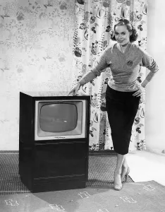 Woman posing next to a television