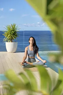 Framed Print : A woman practices meditation on a deck overlooking the ocean Framed Print : A woman practices meditation on a deck overlooking the ocean