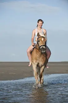 Woman riding bareback on a Haflinger horse on the beach