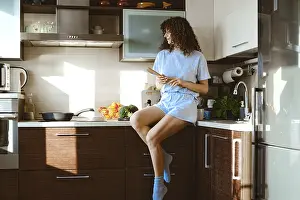 A woman sits on a kitchen counter in a modern home