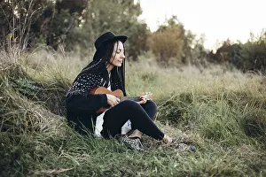 A woman sits peacefully on grass