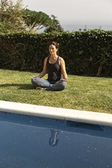 Framed Print : A woman sits by a swimming pool in the Sukhasana pose