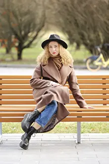 A woman sits on a wooden bench in a park