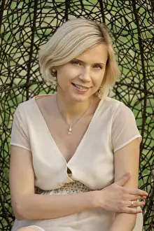A woman is sitting in a woven chair in a garden