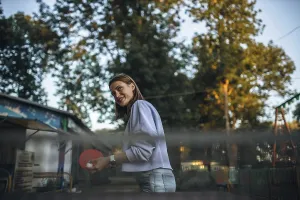 Woman smiling while engaging in table tennis in a park setting
