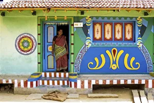 A woman standing at the entrance door of the village house
