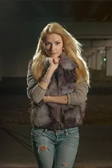 A woman stands confidently in an urban area during the night