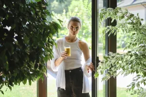 A woman stands in a doorway holding a glass of refreshing beverage