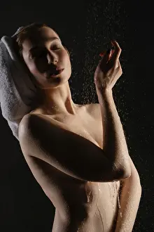 A woman stands gracefully with water cascading down