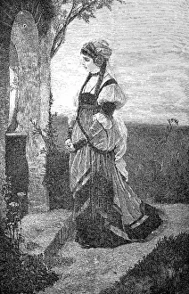 Woman stands in front of a small field chapel and prays