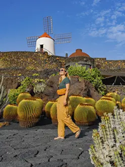 A woman strolls near a traditional windmill surrounded by cacti in Lanzarote