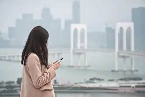 Woman, using phone with Sai Van Bridge in the background