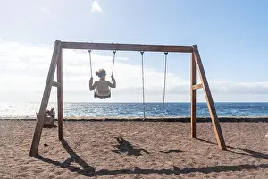 A woman on vacation swinging on a swing on the beach of the island of El Hierro