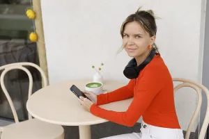 A woman in Warsaw sits at an outdoor cafe She is using her smartphone