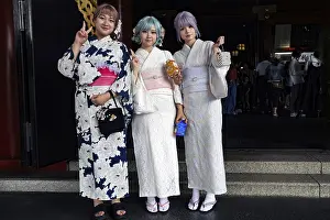 Three woman wearing white kimonos pose in front of Senso-ji in Asakusa