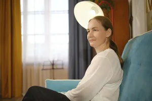 A woman in a white top sits comfortably on a blue couch