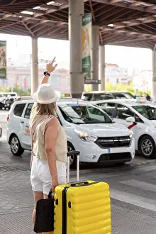 Woman with a yellow suitcase standing at a busy transportation hub