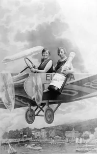 Two women with a bottle of sparkling wine in an aircraft mock-up