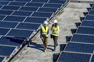 Two women engineers wearing hard hats and high visibility vests walking