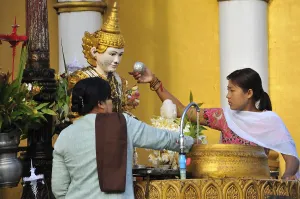 Two women pouring water onto a statue