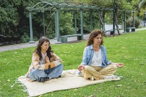 Two women practicing mindfulness and meditation on grass