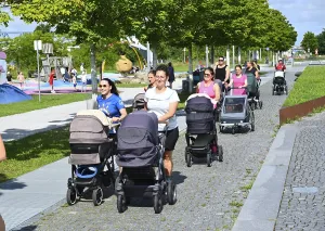 Women pushing prams in a sunny park