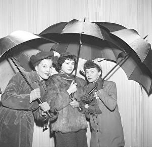 Three women under umbrellas in the 1950s