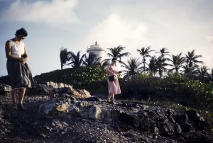 Two women walking on rocky shoreline on the coast at Toco, Trinidad c 1963