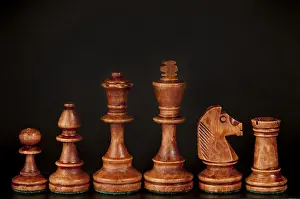 Wooden chess pieces lined up against a dark background