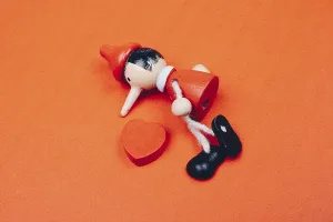 Wooden Pinocchio doll sitting with a heart