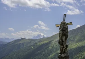 Wooden sculpture Four-man column behind it the Ortler