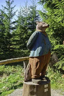 A wooden sculpture of a fox stands in the forest