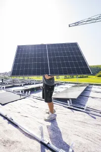 Worker holding a solar module on a sunny roof